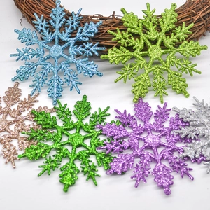 Set of six colorful glittery snowflake ornaments displayed on a woven vine wreath