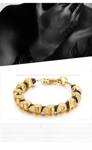 Detail view of men's skull bracelet with black lava stones and golden stainless steel