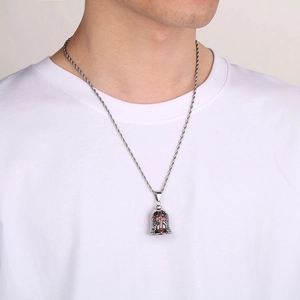 Detailed close-up of a silver bell pendant with red cross and angel wings on a twisted chain