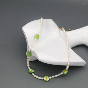 Detail of freshwater pearl necklace with green daisy charms on a white mannequin neck
