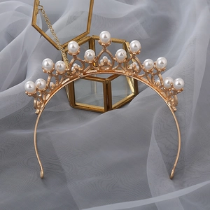 Detailed close-up of golden alloy crown headband with elegant white pearls on soft tulle
