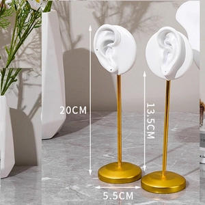 Detailed view of white resin ear model jewelry stands with golden metal rods and bases