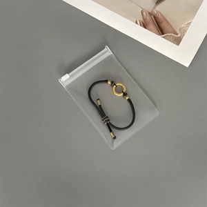 Close-up of a black cord bracelet with gold accents inside a clear EVA jewelry storage pouch