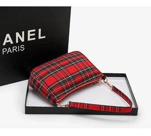 Close-up of red tartan baguette bag with golden hardware and textured fabric
