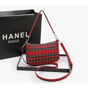 Detailed close-up of red plaid baguette bag with adjustable straps and metal hardware