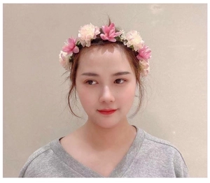 Close-up of pink and cream artificial flower headband worn by a model in soft lighting