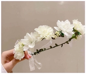 Detail of white bridal flower crown with silk petals, green leaves, and sheer ribbon