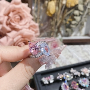 Close-up of heart ring with pink and clear pear-cut stones and 18K gold plated band