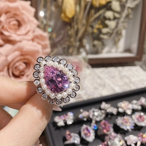 Macro shot of silver ring featuring a pink pear-shaped gemstone with pearl and zircon halo