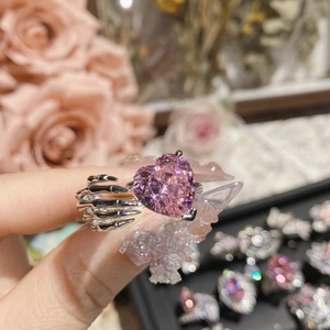 Macro shot of a pink heart-shaped gemstone ring with a unique silver skull hand design