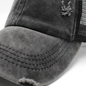 Close-up of washed black trucker hat featuring distressed edges and mesh back details
