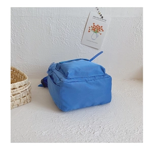 Minimalist blue kindergarten backpack for toddlers against a white textured wall