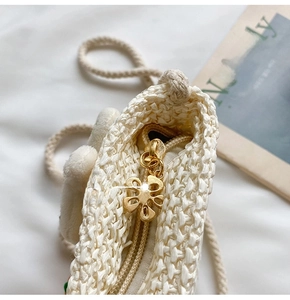 Dettaglio borsa di paglia per bambini con cerniera a fiore dorata e trama intrecciata