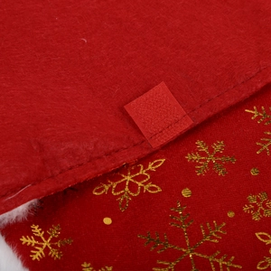 Detail of red felt Christmas tree skirt showing gold snowflake print and velcro fastener