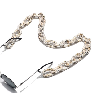 Détail de la chaîne de lunettes en acrylique blanc marbré avec des maillons dorés chics