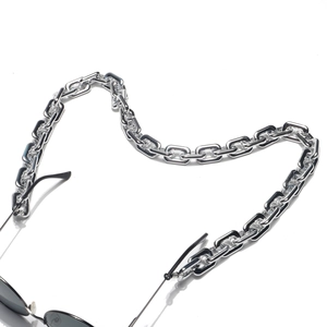 Detail of silver chunky chain eyeglass strap attached to black sunglasses on white base