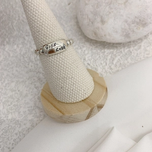 Close-up of silver beaded adjustable ring with Good Luck engraving on display stand