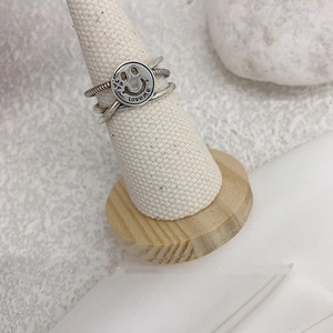 Close-up of vintage silver smiley face ring with Love Me engraving on a cone stand