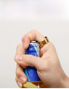 Close-up of a person using a gold stainless steel ring to open a beer bottle cap