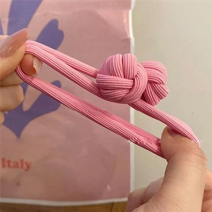 Elastic pink ribbed hair tie with double pineapple knots shown stretched by hand
