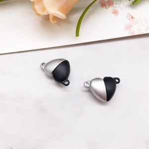 Close-up of heart-shaped magnetic clasp pendants in silver and black on marble surface