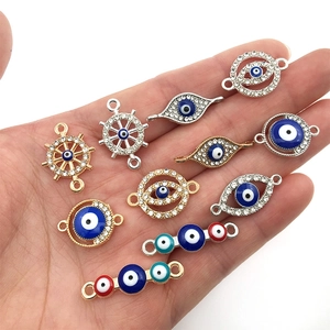 Mix of colorful Evil Eye and Hamsa jewelry connectors with crystals held in hand