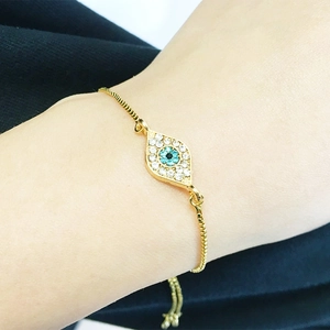 Close-up of a gold adjustable evil eye bracelet with blue rhinestones on a wrist