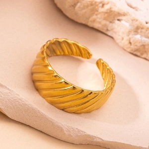 Detailed view of gold textured open ring on a minimalist sandstone background
