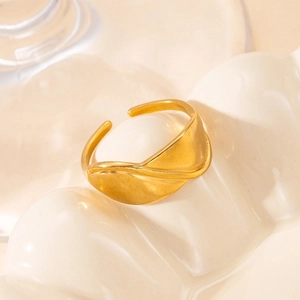 Detailed view of an adjustable gold-plated wave ring on a ceramic tray display