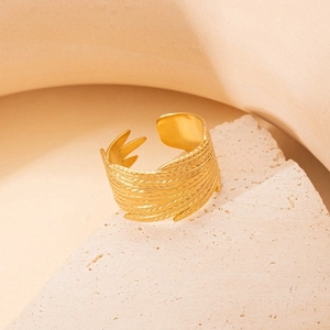 Macro shot of gold feather textured open ring on minimalist stone display