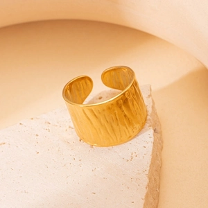 Detail shot of a wide gold titanium steel ring featuring an artistic hammered texture