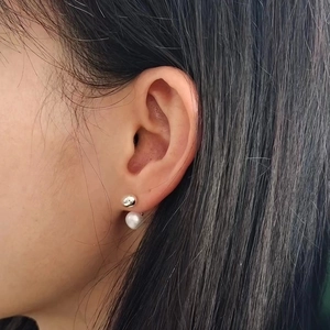 Minimalist gold plated ball and freshwater pearl earring on model in a profile view
