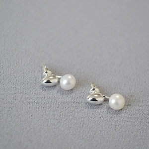 Detailed view of freshwater pearl earrings with polished silver metal on grey fabric