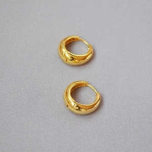 Polierte klobige Gold-Creolen mit minimalistischem, geschwungenem Design auf Grau