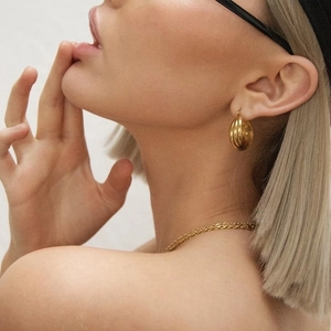 Minimalistische 18K vergoldete Creolen und eine schlanke Kette an einem Model
