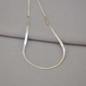 Macro shot of silver flat snake chain necklace with high-polished metallic texture