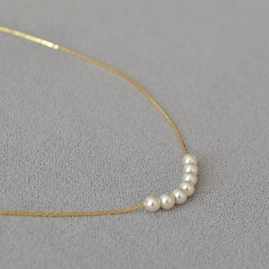 Detail of seven lustrous white pearls on a delicate gold plated chain necklace
