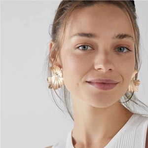 Golden ginkgo leaf earrings with textured fan shape on a model for elegant style