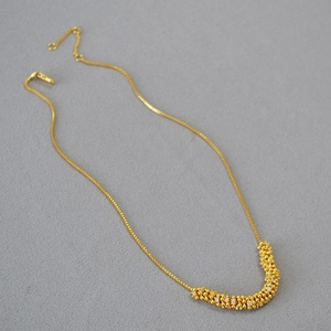 Elegante collana in ottone dorato con pendente in zircone intrecciato su tessuto grigio