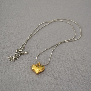 Macro detail of 3D gold heart pendant on silver bead chain minimalist necklace
