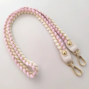Detailed close-up of woven pink and beige cotton bag strap with gold accents and metal hooks