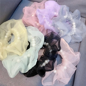 Detail von bunten Organza-Haargummis mit weißen Perlen in weichen Macaron-Farbtönen
