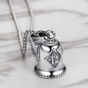 Detailed macro shot of vintage 1%er skull bell pendant with bead chain on marble surface