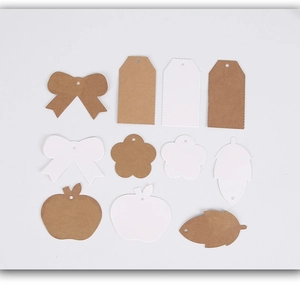 Flat lay of vintage kraft and white paper gift tags in butterfly, flower and leaf shapes