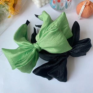 Detailed view of oversized seersucker bow headbands in black and green colors