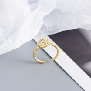 Detail of gold textured hammered ring face with twisted rope band design and open fit