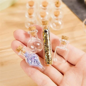 Close-up of mini glass jars in various shapes with cork stoppers held in a hand