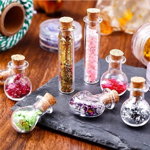 Macro shot of mini DIY glass bottles with cork stoppers and colorful glitter on stone