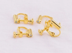 Detailed macro view of four golden U-shaped clip-on earring converters on white fabric