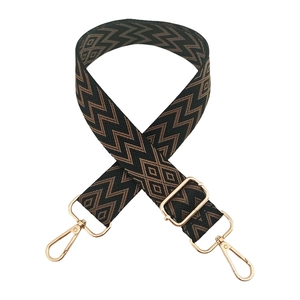 Detail of adjustable woven shoulder strap with brown diamond patterns and gold hooks
